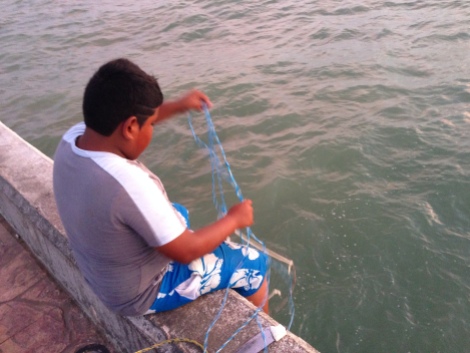 Foto: MugsNoticias. Un niño realiza pesca artesanal en Puerto Progreso, Yucatán. En el malecón, decenas de hombres y mujeres realizan esta práctica a lo largo del día.
